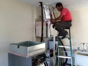 Coolco employee sitting on top of a ladder servicing a commercial AC unit