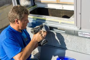 Coolco employee using a drill on an AC unit