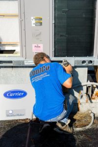 Coolco employee using a drill on an industrial AC unit