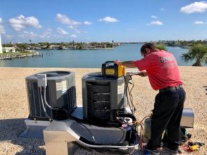 Coolco employee servicing two AC units on the beach