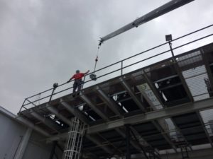 Coolco employee on a high platform directing a crane