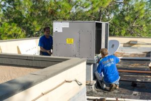 Two Coolco employees working on a rooftop AC unit